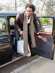 London shoppers; cab journey. A young man alights from a London taxi after a day out shopping. From...