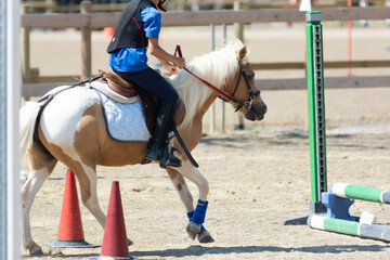 Little girl that rides a white pony during Pony Game competition at the Equestrian School