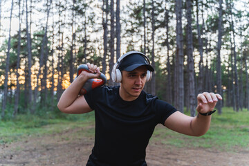 A young man training in the forest during the golden hour stretching and measuring pulse while enjoying nature