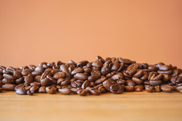 close up of heap roasted coffee beans on  brown wood desk with selective focus