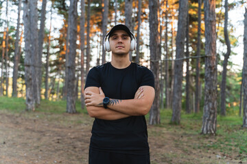 A young man training in the forest during the golden hour stretching and measuring pulse while enjoying nature