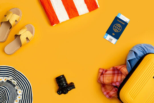 Flat Lay Shot Of Yellow Suitcase Unpacked With Holiday Accessories On Yellow Background