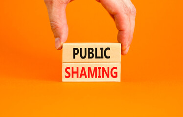 Public shaming symbol. Concept words Public shaming on wooden blocks on a beautiful orange table orange background. Businessman hand. Business and public shaming concept. Copy space.