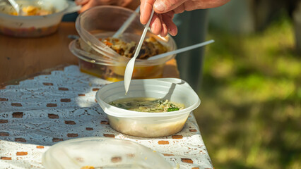 Volunteers distribute food to the poor outdoors, selective focus