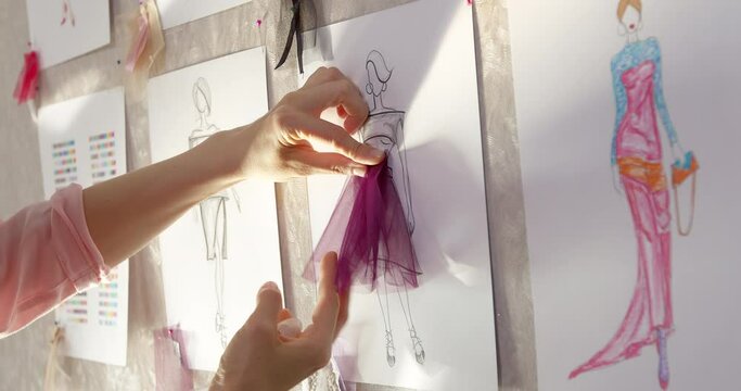 The fashion designer develops sketches of clothing design. The artist creates women's dresses. Tailor working with fabric.