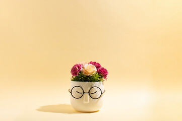 Cup of hot drink with a flowers inside on a yellow background. Minimal spring ,summer concept.