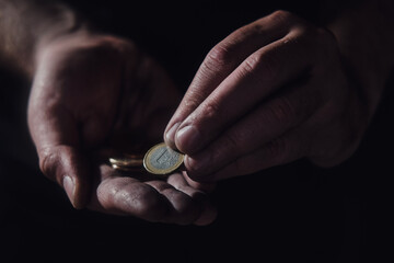 Man hands holding euro money on a black background, close-up. European cash in the dirty hands of a...