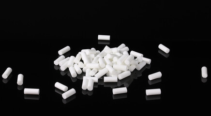 White cigarette filters on a dark table with reflection. Close-up