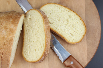 Flat-lay of freshly baked bread loaf and bread slices on rustic wooden board