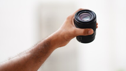 image of camera lens holding in hand vertically.