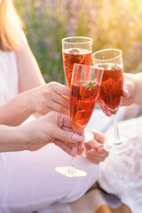 Three girls clink glasses with sparkling wine and strawberries inside at a picnic
