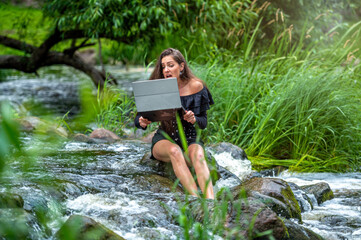 worried woman pulls out of water laptop that fell into river, remote holiday work accident
