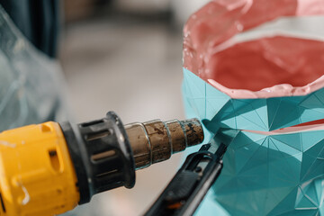 Artisan sculptor artist uses an industrial hair dryer in creating a work of art in his workshop