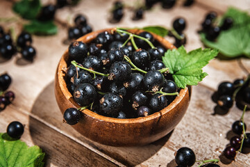 black currants in a bowl on a wooden background. berries, summer, vitamins, healthy natural food. top view