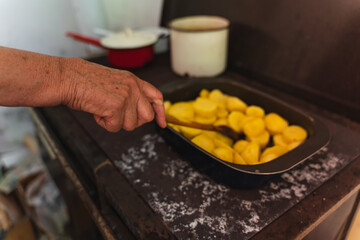Close up of wrinkled old hands peeling and preparing potatoes for lunch