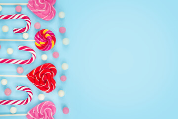 sweets, candies, cookies and lollipops on a blue background. Sweet hearts Christmas canes. Top view copy space