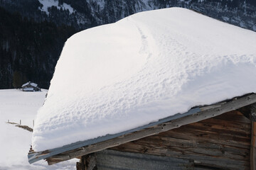 white snowdrift on the slope of a wooden roof, beautiful white landscape, danger of snow falling...