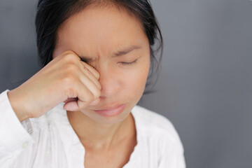 A young woman rubs her eyes due to irritants such as dust, smoke, and chemicals getting into her...