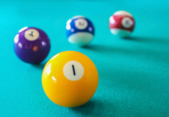 A number 1 yellow billiard at a green pool table surface with blurred background of colorful balls. Indoor sport and recreation, competitive and winner achieve concept. Game challenge. - Powered by Adobe
