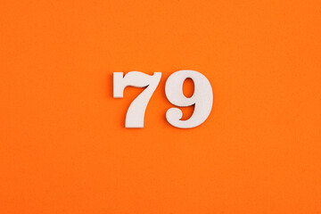 White wooden number 79 on eva rubber orange background