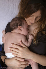 Loving mother holding and hugging her newborn boy taking so much care of him