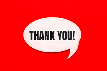 On a bright red background, a light wooden curly card with the text THANK YOU
