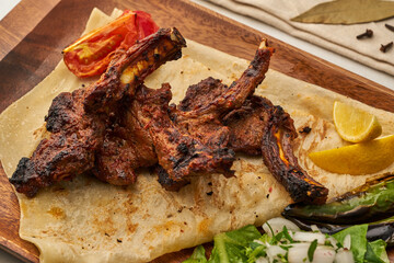 spicy lamb chops with pita bread served in a dish isolated on grey background side view of fastfood