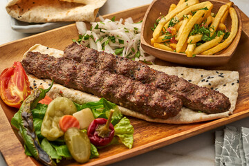 Lamb Kebab with fries, pita bread and lime served in a dish isolated on grey background side view...