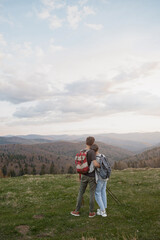 Fototapeta na wymiar Rear on couple standing on top of mountain and enjoying beautiful view in hugs. Hikers.