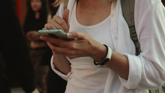 Woman using smartphone at evening street, Female typing message, browsing internet while walking at city.