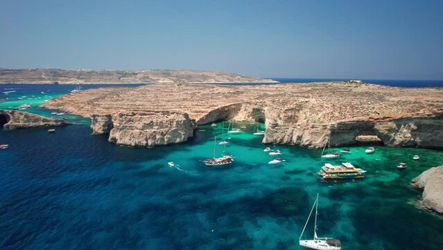 4K drone footage of the nature of Malta - Blue Lagoon on Comino, Mediterranean Sea. Yachts sailing,people swimming. The drone slowly turns around Crystal Lagoon and opened view to the blue lagoon.