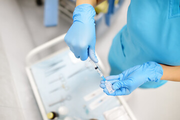 The female surgeon is dialing medicine into a syringe. Doctor is preparing to give an injection to...