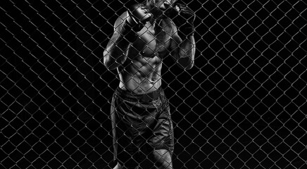 Black and white image of a man in a boxing cage. The concept of sports, Muay Thai, martial arts.