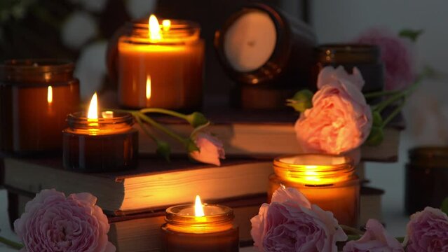 A set of different aroma candles in brown glass jars and flowers. Scented handmade candle. Soy candles are burning in a jar. Aromatherapy and relax in spa and home. Fire in brown jar. Dark evening