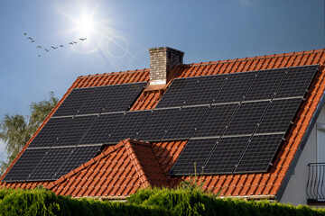 A large number of black solar panels on the red tile roof. Photovoltaics, panels on red tile roofs....