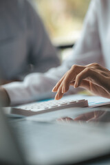 A businessman is using a white calculator to calculate financial numbers, he is sitting in his...