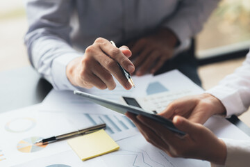 Two businessmen are brainstorming together and reviewing the company financial documents that the finance department has summarized, they are business partners. Business administration concept.