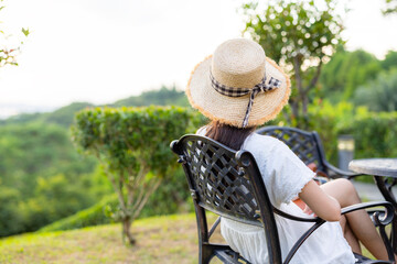 Woman sit on outdoor chair and look outside