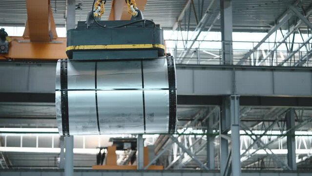 Loading sheet metal in a warehouse using a crane and an electromagnet. Fast work of the warehouse, rolled metal products.