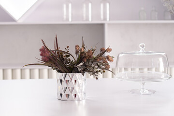 Grey glass vase and decorative floral elements on a white table