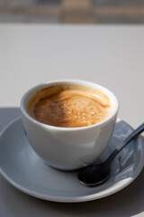 Small white cup of black arabica coffee served outdoor