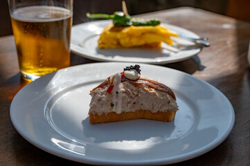 Sunny day in San Sebastián, typical food and drink in bars of Basque Country, pinchos or pinxtos, small slices of bread with different toppings and glass of beer, lunch in Spain