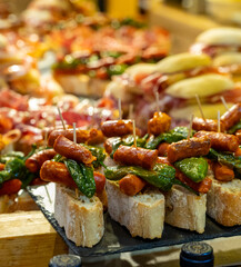 Typical snack of Basque Country and Navarre, pinchos or pinxtos, small piece of bread with different toppings, served in bar, Bilbao, Spain