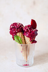 Vegan beetroot ice cream in a waffle cone in a glass with sesame. Styling with fresh leaves and a piece of beet. Healthy vegan frozen dessert.  - obrazy, fototapety, plakaty