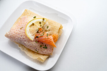 Cuisine of Normandy, galette pancake filled with goat cheese and smoked salmon served with fresh lemon