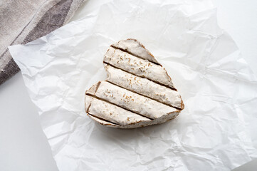 French heartshaped neufchatel cow cheese with mold on white paper, Normandy, France