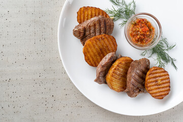 Meat with fried potatoes. The potatoes are cut like chips.