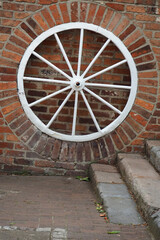 texture background of brick wall and old carriage wheel painted white with copy space 