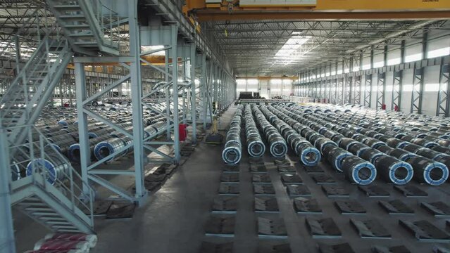 Industrial warehouse of a metallurgical enterprise. Rolled metal products are stored in rows in a warehouse.