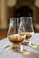Two glasses of scotch whiskey with view on fireplace in old house on background, Edinburgh whisky tasting tour, Scotland